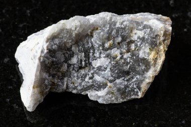 Siyah granit zemin üzerinde kaba melilite (melilite-monticellite metasomatite) kaya örneği yakın plan