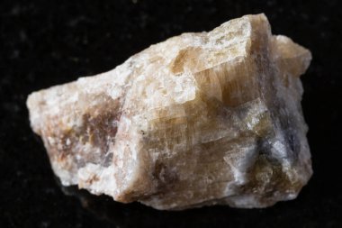 Siyah granit arka planda ham kancrinit minerali örneği. Rusya, Güney Urallar 'dan yakın plan.