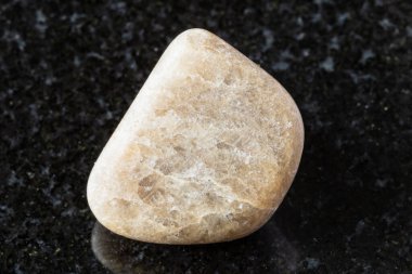 Siyah granit zemin üzerinde cilalanmış kriyolit kaya örneği. Rusya, Tuva 'dan yakın plan.