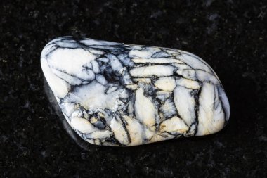 Siyah granit arka planda parlatılmış pinolit minerali örneği. Avusturya 'dan yakın plan.