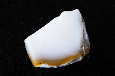 Siyah granit arka planda kaba beyaz opal mineral örneği yakın plan