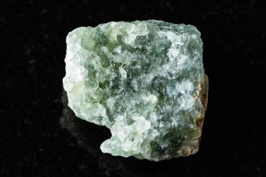 Siyah granit arka planda işlenmemiş yeşil bulvar minerali örneği yakın plan