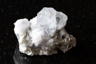 Siyah granit arka planda mika ve feldspar kaya içeren pürüzsüz renksiz beril (Goshenite) örneği Çin 'in Sichuan kentinden