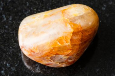 Siyah granit zemin üzerinde cilalanmış turuncu kuvars taşı örneği. Rusya, Güney Urallar 'dan yakın plan.