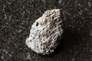 Sicilya yakınlarındaki siyah granit arka planda ham sünger taşı örneği.