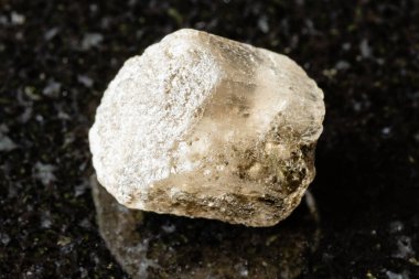 Siyah granit zemin üzerinde ham fenakit kaya örneği. Orta Urallar, Rusya 'dan yakın plan.