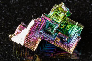 Siyah granit arka planda kaba yetişmiş bizmut kristalleri minerali örneği yakın plan