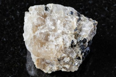 Rusya, Doğu Sibirya 'dan yakın arkaplanda siyah granit zemin üzerinde annit mika bulunan ham kriyolit kaya örneği