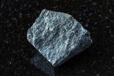 Rusya, Karelia 'dan yakın arkaplandaki siyah granit üzerine işlenmemiş peridotik komatit minerali örneği