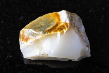 Siyah granit arka planda ham beyaz opal mineral örneği yakın plan