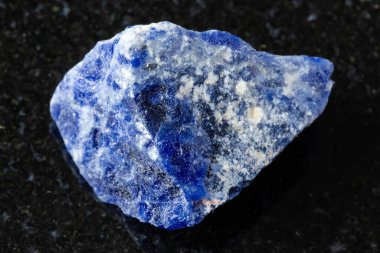 Siyah granit arka planda işlenmemiş sodalit minerali örneği yakın plan
