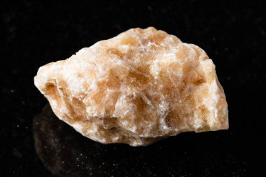 Siyah granit zemin üzerinde işlenmemiş kahverengi kalsit kayası örneği yakın plan