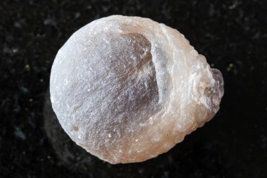 Siyah granit arka planda cilalanmamış akik mineral örneği yakın plan