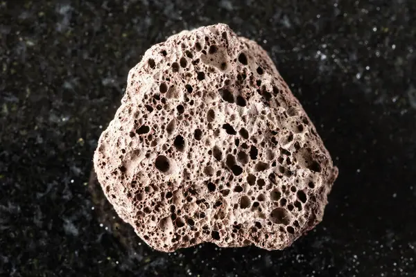 Siyah granit arka planda kaba kahverengi sünger taşı minerali örneği yakın plan