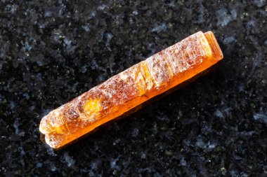 Siyah granit zemin üzerinde kaba turuncu kyanit kristali örneği Tanzanya 'dan yakın mesafede.