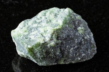 Siyah granit zemin üzerinde çiğ yeşil nefrit taşı örneği yakın plan