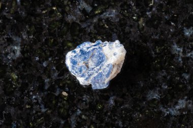 Siyah granit arka planda kaba mavi spinel kristal örneği. Vietnam 'dan yakın plan.