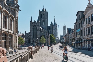 The facade of Saint Nicholas` Church Sint-Niklaaskerk, with the clock tower of the Belfry of Ghent Het Belfort in the background, is in Ghent, Belgium, Europe.
