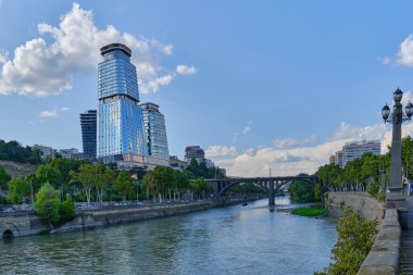  Eski bir nehir barajı, modern gökdelenlerin zeminine karşı kemerli taş bir köprü ve bulutlu güzel bir gökyüzü: Tiflis, Georgia 