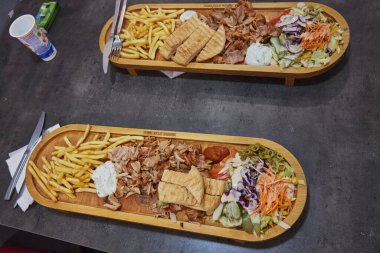 Doener kebab on a wooden tray with French fries and salad