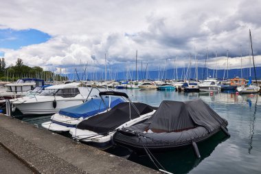 Sailboats are anchored along the pier at the port on Lake Geneva. Bad weather and heavy clouds caused yachts to leave the marina