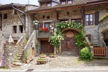 House in Yvoire, France, with stones and pots on a cloudy day.