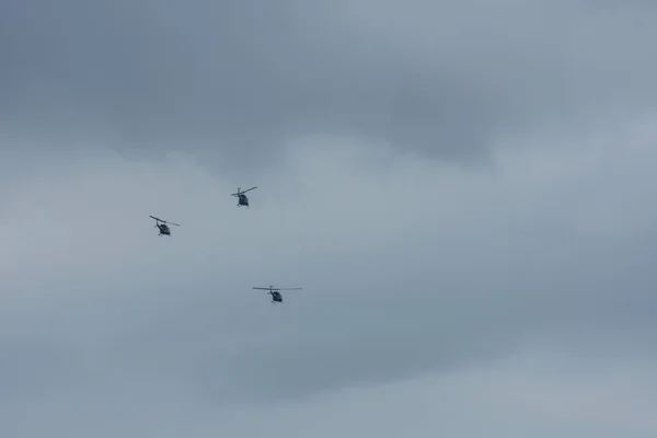 三架直升机带着雨云在灰蒙蒙的天空中飞行 — 图库照片