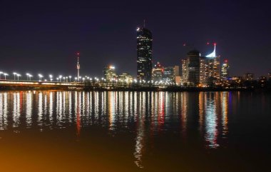 view to illuminated scyscrapers and their reflections in the water from the danube in vienna