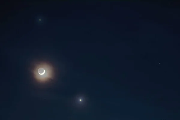 moon with a colored glow and two stars next to it at the night sky