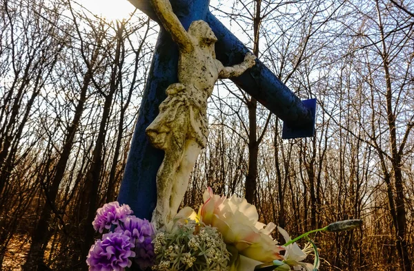 stock image cross with jesus and fresh flowers on a mountain with forest during hiking