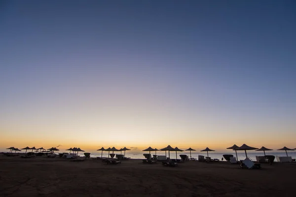 在海滩日出的时候 有着惊人的色彩 有大量的雨伞和埃及式的日光浴床 — 图库照片