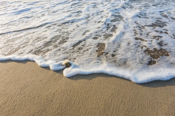 从宏观上看日出时沙滩上的细沙上的白沫波涛 — 图库照片