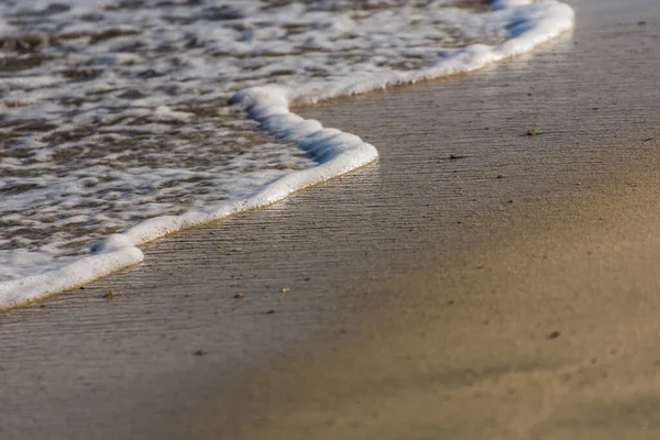 从海浪中喷出的白色泡沫在沙滩上的埃及宏观视图 — 图库照片