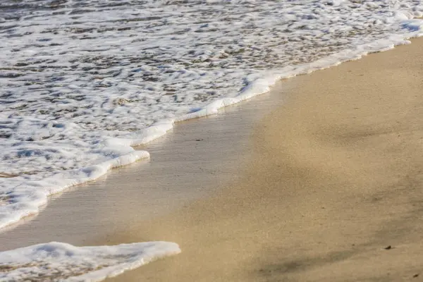 白沫从沙滩上的波浪中隐约看到 — 图库照片