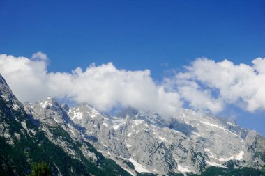 Mavi gökyüzünde beyaz bulutlar yüksek kayalık dağların üzerinde ve Salzburg Avustralya 'da kar var.