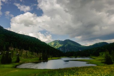 Bir sürü yeşil çayır ve bulutlu dağ gölü. Avustralya 'da mavi gökyüzüne yağmur yağıyor.