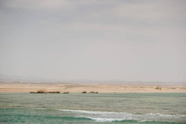 Yüzeyinde mercan resifleri ve arka planında Mısır 'daki çöl olan plaj.