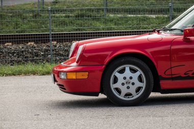 Yazın bir araba fuarı sırasında eski kırmızı bir arabanın önünde.