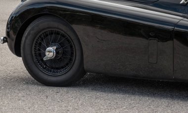 Bir araba fuarında siyah tekerlekleri olan çok eski siyah klasik bir arabanın ayrıntıları.