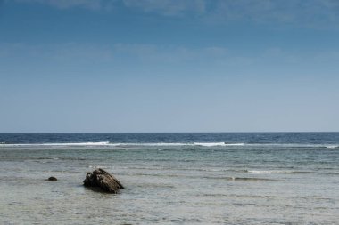 Denizdeki mercan resifinde tek bir kaya. Mavi gökyüzü tatilde.