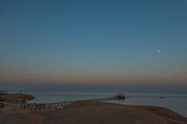 Gün batımından sonra sahilde mavi saat ve tatilde plajda insanlarla oynamak.