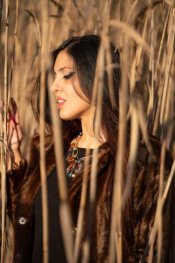 Güz parkında poz veren güzel esmer kadın.