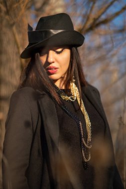 Parkta zinciri olan şık elbiseli güzel, esmer bir kadın. Güneşli bir günde portre