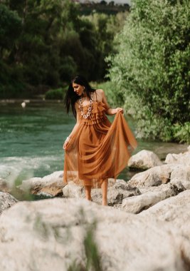 Dağlarda poz veren beyaz elbiseli güzel bir kadın.