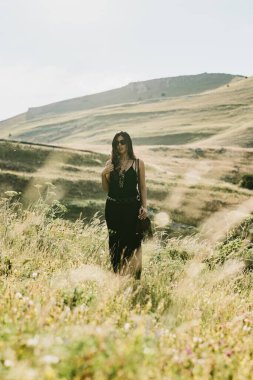 Güzel bir kadının dağda elinde çanta ve kolyeyle yürüyüşünü yakından izle.