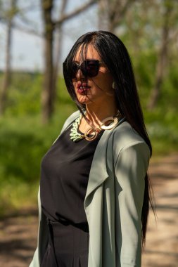 Dışarıda poz veren güneş gözlüklü genç bir kadın..