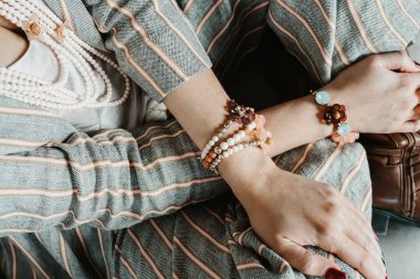 Ahşap bir masada mücevher takan kadın elleri