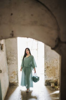 Eski binada yeşil elbiseli genç bir kadın var..