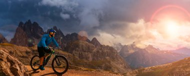 İtalya 'da Dolomitler' de bir adam elektrikli dağ bisikletlerine biniyor. Dağ bisikleti macerası güzel dağ patikalarında.