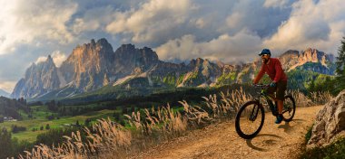 İtalya 'da Dolomitler' de bir adam elektrikli dağ bisikletlerine biniyor. Dağ bisikleti macerası güzel dağ patikalarında.